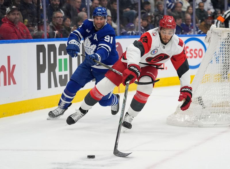 Nov 9, 2025; Toronto, Ontario, CAN; Carolina Hurricanes defenseman K'Andre Miller (19) tries to get control of the puck as Toronto Maple Leafs forward John Tavares (91) checks him during the third period at Scotiabank Arena. Mandatory Credit: John E. Sokolowski-Imagn Images