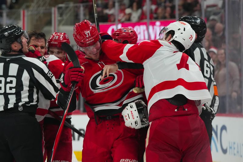 Feb 28, 2026; Raleigh, North Carolina, USA;  Carolina Hurricanes right wing Andrei Svechnikov (37) and Detroit Red Wings center Dylan Larkin (71) battle during the second period at Lenovo Center. Mandatory Credit: James Guillory-Imagn Images