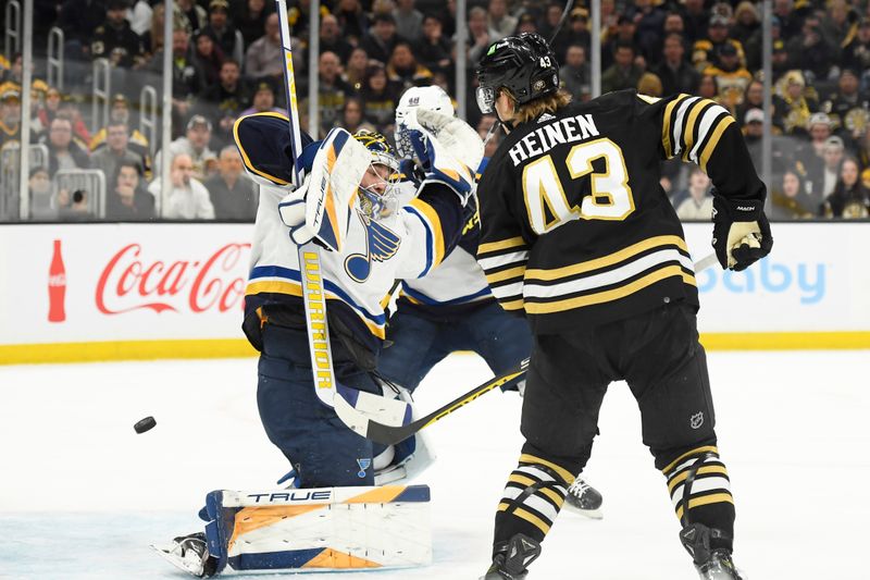 Mar 11, 2024; Boston, Massachusetts, USA;  St. Louis Blues goaltender Joel Hofer (30) makes a save while Boston Bruins left wing Danton Heinen (43) looks for a rebound during the first period at TD Garden. Mandatory Credit: Bob DeChiara-USA TODAY Sports