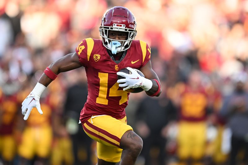 Nov 4, 2023; Los Angeles, California, USA; USC Trojans cornerback Jacobe Covington (14) carries the ball to score a touch down against the Washington Huskies during the first quarter at United Airlines Field at Los Angeles Memorial Coliseum. Mandatory Credit: Jonathan Hui-USA TODAY Sports