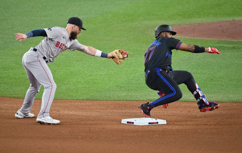 Sep 25, 2024; Toronto, Ontario, CAN;  Toronto Blue Jays first baseman Vladimir Guerrero Jr. (27) eludes a tag from Boston Red Sox shortstop Trevor Story (10) after hitting a double in the fourth inning at Rogers Centre. Mandatory Credit: Dan Hamilton-Imagn Images