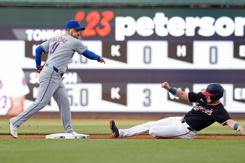 Jun 4, 2024; Washington, District of Columbia, USA; New York Mets shortstop Jose Iglesias (11) turns a double play at second base ahead of a slide by Washington Nationals outfielder Lane Thomas (28) during the first inning at Nationals Park. Mandatory Credit: Geoff Burke-USA TODAY Sports