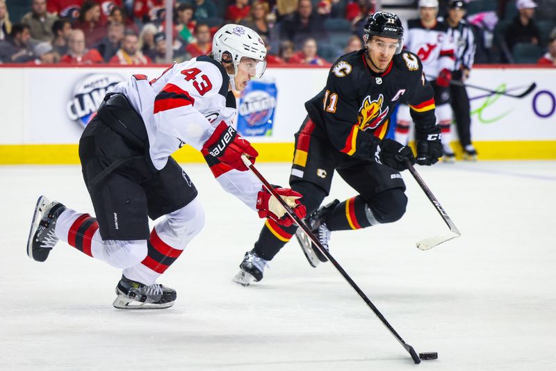 Dec 9, 2023; Calgary, Alberta, CAN; New Jersey Devils defenseman Luke Hughes (43) skates with the puck in front of Calgary Flames center Mikael Backlund (11) during the second period at Scotiabank Saddledome. Mandatory Credit: Sergei Belski-USA TODAY Sports