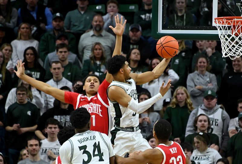 Feb 25, 2024; East Lansing, Michigan, USA;  Michigan State Spartans guard Jaden Akins (3) scores past Ohio State Buckeyes forward Devin Royal (21) during the first half at Jack Breslin Student Events Center. Mandatory Credit: Dale Young-USA TODAY Sports