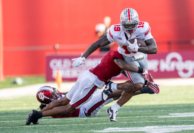 Sep 2, 2023; Bloomington, Indiana, USA; Ohio State Buckeyes running back Chip Trayanum (19) is tackled by Indiana Hoosiers defensive back Kobee Minor (5) during the second half at Memorial Stadium. Mandatory Credit: Marc Lebryk-USA TODAY Sports