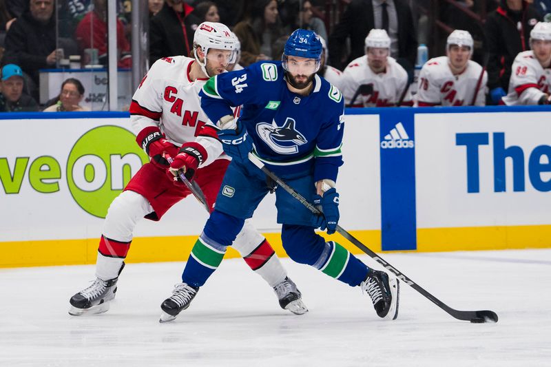 Dec 9, 2023; Vancouver, British Columbia, CAN; Carolina Hurricanes defenseman Jaccob Slavin (74) defends against Vancouver Canucks forward Phillip Di Giuseppe (34) in the first period at Rogers Arena. Mandatory Credit: Bob Frid-USA TODAY Sports