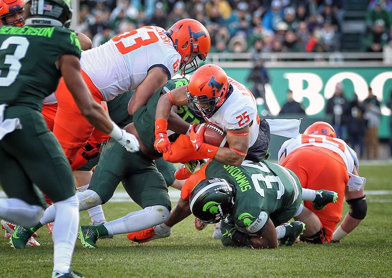 Nov 9, 2019; East Lansing, MI, USA; Illinois Fighting Illini running back Dre Brown (25) is tackled by Michigan State Spartans linebacker Antjuan Simmons (34) during the first quarter of a game at Spartan Stadium. Mandatory Credit: Mike Carter-USA TODAY Sports