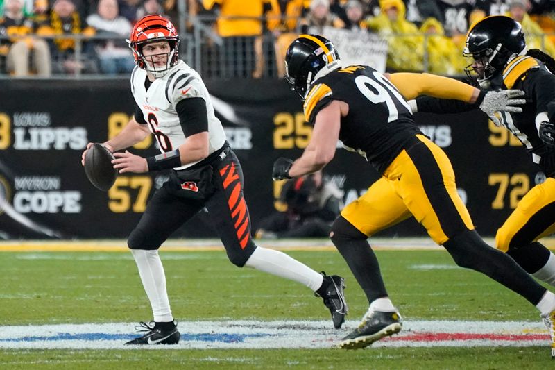 Cincinnati Bengals quarterback Jake Browning (6) rolls out looking to pass under pressure from Pittsburgh Steelers linebacker T.J. Watt (90) during an NFL football game against the Pittsburgh Steelers in Pittsburgh, Saturday Dec. 23, 2023. (AP Photo/Gene J. Puskar)