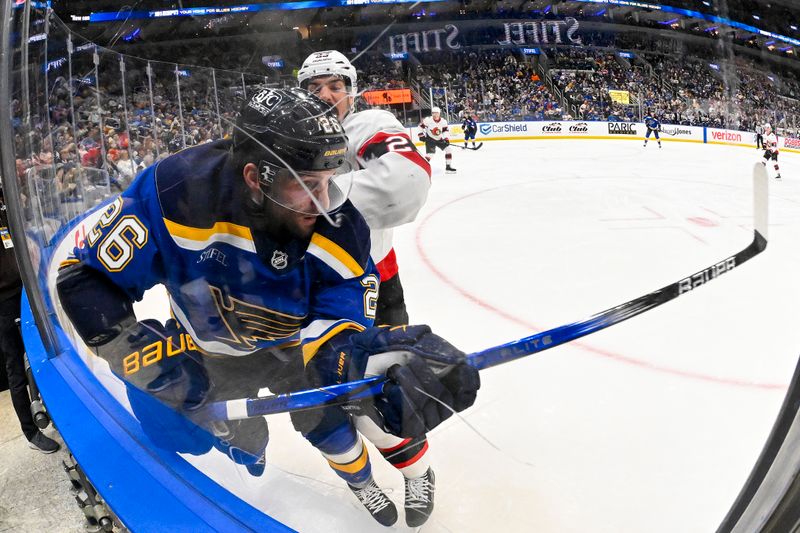 Jan 3, 2025; St. Louis, Missouri, USA;  St. Louis Blues left wing Nathan Walker (26) is checked by Ottawa Senators defenseman Travis Hamonic (23) during the second period at Enterprise Center. Mandatory Credit: Jeff Curry-Imagn Images