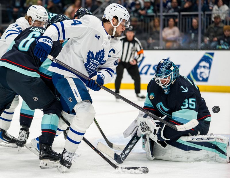 Jan 29, 2026; Seattle, Washington, USA; Toronto Maple Leafs forward Auston Matthews (34), second from right, takes a shot against Seattle Kraken goalie Joey Daccord (35) during the first period at Climate Pledge Arena. Mandatory Credit: Stephen Brashear-Imagn Images