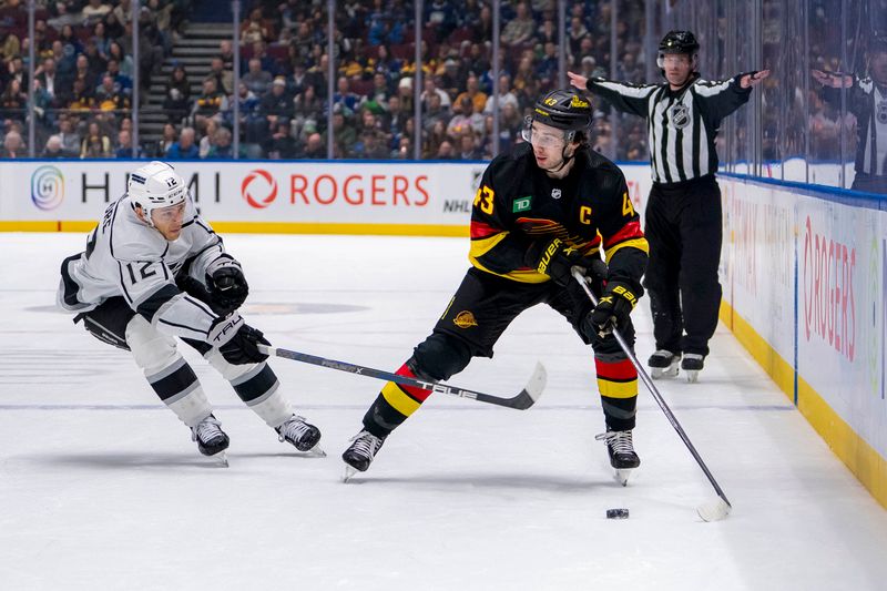 Mar 25, 2024; Vancouver, British Columbia, CAN; Los Angeles Kings forward Trevor Moore (12) stick checks Vancouver Canucks defenseman Quinn Hughes (43) in the first period at Rogers Arena. Mandatory Credit: Bob Frid-USA TODAY Sports