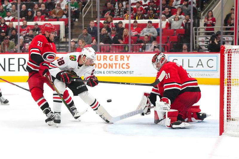 Jan 22, 2026; Raleigh, North Carolina, USA;  Carolina Hurricanes goaltender Frederik Andersen (31) with left wing Nikolaj Ehlers (27) stops the shot by Chicago Blackhawks left wing Andre Burakovsky (28) during the overtime at Lenovo Center. Mandatory Credit: James Guillory-Imagn Images