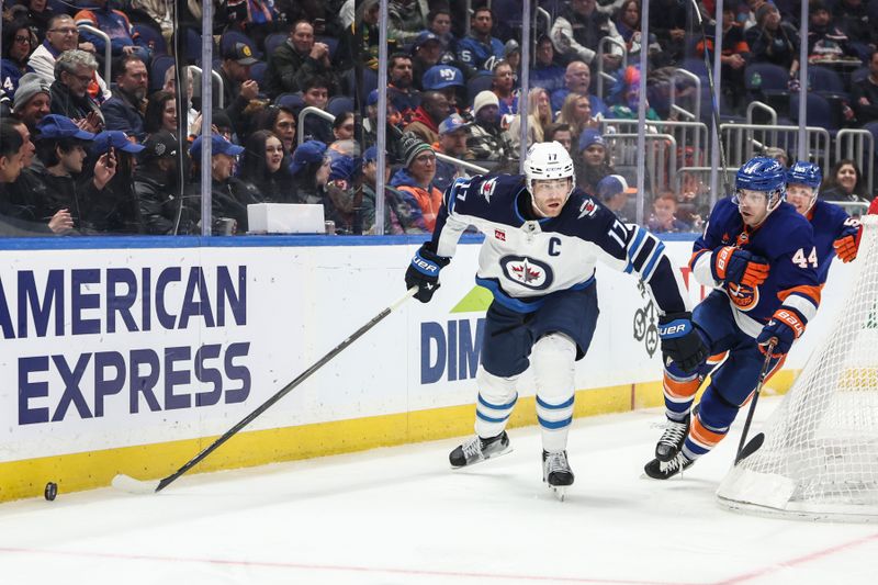 Mar 4, 2025; Elmont, New York, USA;  Winnipeg Jets center Adam Lowry (17) and New York Islanders center Jean-Gabriel Pageau (44) chase after the puck in the second period at UBS Arena. Mandatory Credit: Wendell Cruz-Imagn Images
