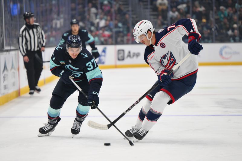 Nov 12, 2024; Seattle, Washington, USA; Seattle Kraken center Yanni Gourde (37) and Columbus Blue Jackets defenseman Damon Severson (78) play the puck during the first period at Climate Pledge Arena. Mandatory Credit: Steven Bisig-Imagn Images