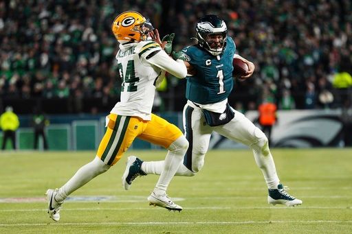 Philadelphia Eagles quarterback Jalen Hurts (1) stiff arms Green Bay Packers cornerback Carrington Valentine (24) during the second half of an NFL wild-card playoff football game Sunday, Jan. 12, 2025, in Philadelphia. (AP Photo/Derik Hamilton)