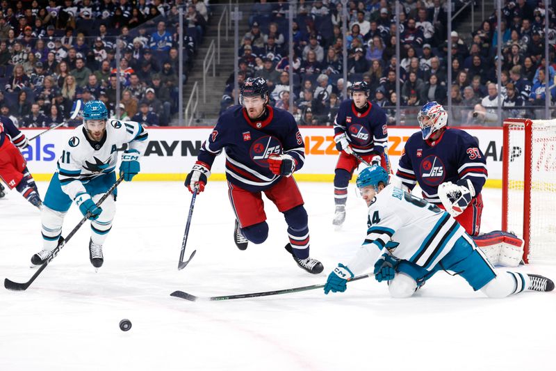 Feb 14, 2024; Winnipeg, Manitoba, CAN; San Jose Sharks center Luke Kunin (11), Winnipeg Jets defenseman Dylan Samberg (54) and San Jose Sharks left wing  Alexander Barbanov (94) chase down the puck in front of Winnipeg Jets goaltender Connor Hellebuyck (37) in the first period at Canada Life Centre. Mandatory Credit: James Carey Lauder-USA TODAY Sports