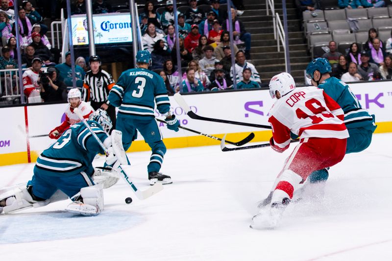 Nov 2, 2025; San Jose, California, USA;  San Jose Sharks goaltender Alex Nedeljkovic (33) deflects a shot by Detroit Red Wings center Andrew Copp (18) during the second period at SAP Center at San Jose. Mandatory Credit: John Hefti-Imagn Images