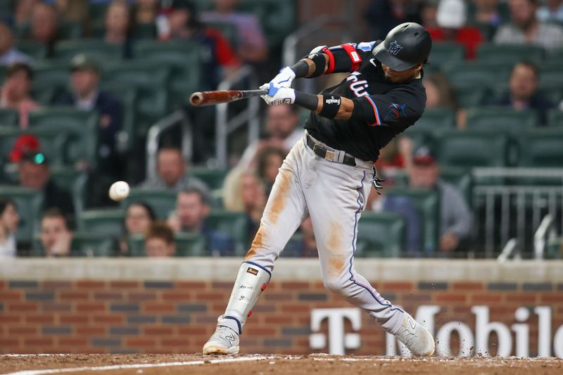 Apr 24, 2024; Atlanta, Georgia, USA; Miami Marlins second baseman Luis Arraez (3) hits a single against the Atlanta Braves in the ninth inning at Truist Park. Mandatory Credit: Brett Davis-USA TODAY Sports