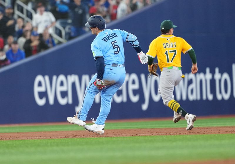 May 31, 2025; Toronto, Ontario, CAN; Toronto Blue Jays centre fielder Daulton Varsho (5) grabs his left leg after rounding second base against the Athletics during the third inning at Rogers Centre. Mandatory Credit: Nick Turchiaro-Imagn Images