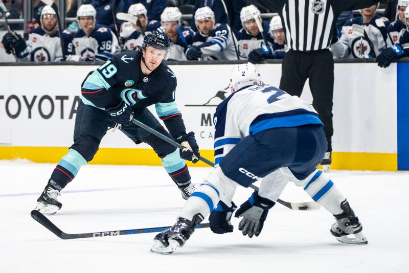 Oct 24, 2024; Seattle, Washington, USA;  Seattle Kraken forward Jared McCann (19) skates against Winnipeg Jets defenseman Dylan DeMelo (2) during the first period at Climate Pledge Arena. Mandatory Credit: Stephen Brashear-Imagn Images