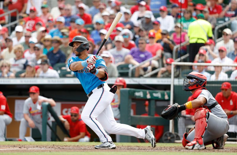 Mar 16, 2025; Jupiter, Florida, USA;  Miami Marlins left fielder Heriberto Hernandez (78) follows through on his RBI double in front of St. Louis Cardinals catcher Ivan Herrera (48) during the second inning  at Roger Dean Chevrolet Stadium. Mandatory Credit: Rhona Wise-Imagn Images