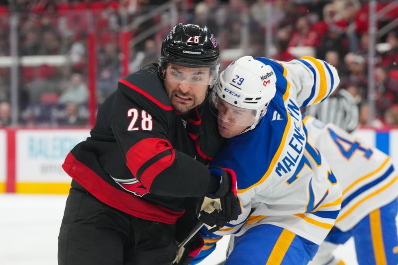 Jan 19, 2026; Raleigh, North Carolina, USA;  Buffalo Sabres left wing Beck Malenstyn (29) and Carolina Hurricanes left wing William Carrier (28) battle for position during the first period at Lenovo Center. Mandatory Credit: James Guillory-Imagn Images