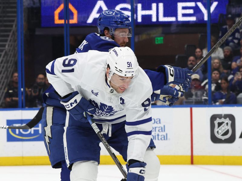 Apr 9, 2025; Tampa, Florida, USA; Tampa Bay Lightning defenseman Nick Perbix (48) and Toronto Maple Leafs center John Tavares (91) fight to control the puck during the second period at Amalie Arena. Mandatory Credit: Kim Klement Neitzel-Imagn Images