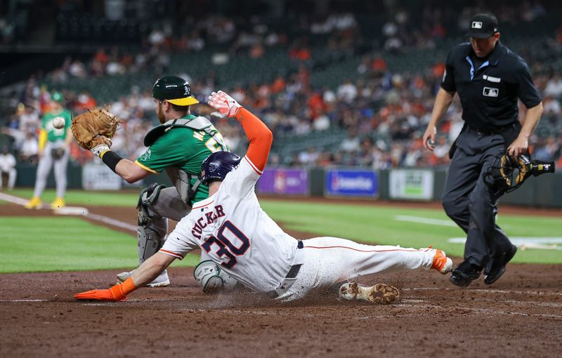 May 16, 2024; Houston, Texas, USA; Houston Astros right fielder Kyle Tucker (30) slides to score a run as Oakland Athletics catcher Kyle McCann (52) fields the throw during the fourth inning at Minute Maid Park. Mandatory Credit: Troy Taormina-USA TODAY Sports