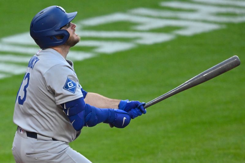May 26, 2025; Cleveland, Ohio, USA; Los Angeles Dodgers third baseman Max Muncy (13) hits an RBI sacrifice fly ball in the fifth inning against the Cleveland Guardians at Progressive Field. Mandatory Credit: David Richard-Imagn Images