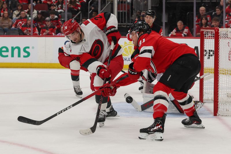 Jan 4, 2026; Newark, New Jersey, USA; New Jersey Devils right wing Arseny Gritsyuk (81) and Carolina Hurricanes defenseman Sean Walker (26) battle for the puck during the second period at Prudential Center. Mandatory Credit: Ed Mulholland-Imagn Images