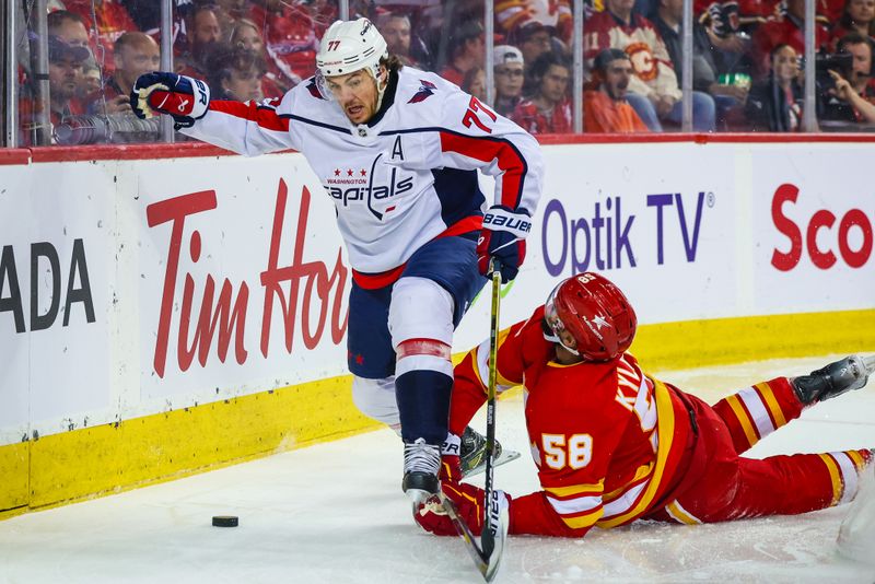 Mar 18, 2024; Calgary, Alberta, CAN; Washington Capitals right wing T.J. Oshie (77) and Calgary Flames defenseman Oliver Kylington (58) battles for the puck during the first period at Scotiabank Saddledome. Mandatory Credit: Sergei Belski-USA TODAY Sports