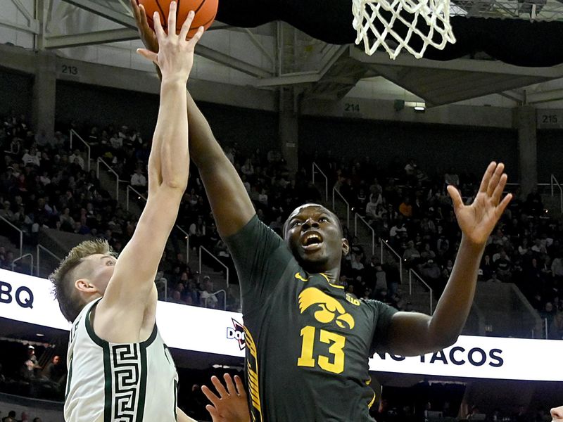 Feb 20, 2024; East Lansing, Michigan, USA;  Michigan State Spartans forward Jaxon Kohler (0) gets his hand on a shot by Iowa Hawkeyes forward Ladji Dembele (13) during the first half at Jack Breslin Student Events Center. Mandatory Credit: Dale Young-USA TODAY Sports
