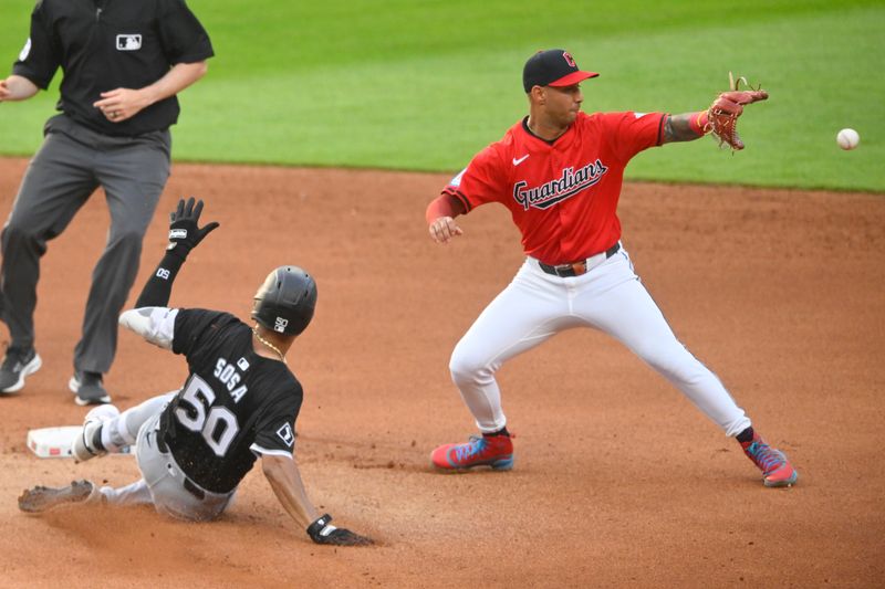 Jul 3, 2024; Cleveland, Ohio, USA; Cleveland Guardians shortstop Brayan Rocchio (4) reaches for the ball as Chicago White Sox third baseman Lenyn Sosa (50) slide to second base on a double in the fourth inning at Progressive Field. Mandatory Credit: David Richard-USA TODAY Sports