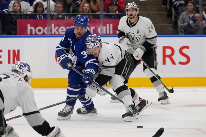 Oct 31, 2023; Toronto, Ontario, CAN; Los Angeles Kings defenseman Mikey Anderson (44) keeps Toronto Maple Leafs forward Auston Matthews (34) away from the puck during the third period at Scotiabank Arena. Mandatory Credit: John E. Sokolowski-USA TODAY Sports