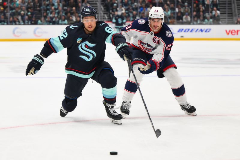 Nov 12, 2024; Seattle, Washington, USA; Seattle Kraken defenseman Brandon Montour (62) and Columbus Blue Jackets center Sean Monahan (23) chase the loose puck during the first period at Climate Pledge Arena. Mandatory Credit: Steven Bisig-Imagn Images