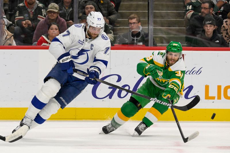 Nov 1, 2024; Saint Paul, Minnesota, USA;  Tampa Bay Lightning defenseman Victor Hedman (77) clears the puck while Minnesota Wild forward Ryan Hartman (38) gives chase during the second period at Xcel Energy Center. Mandatory Credit: Nick Wosika-Imagn Images