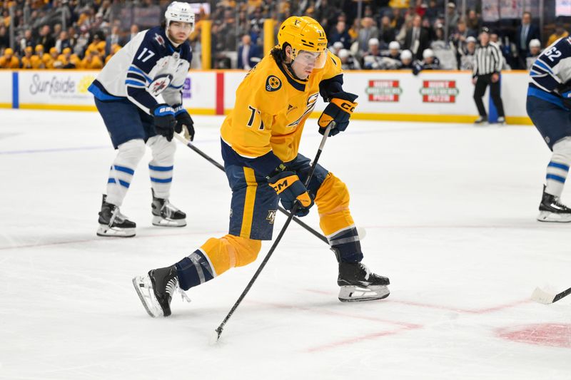 Nov 29, 2025; Nashville, Tennessee, USA;  Nashville Predators right wing Luke Evangelista (77) shoots the puck against Winnipeg Jets defenseman Adam Lowry (17) during the first period at Bridgestone Arena. Mandatory Credit: Steve Roberts-Imagn Images