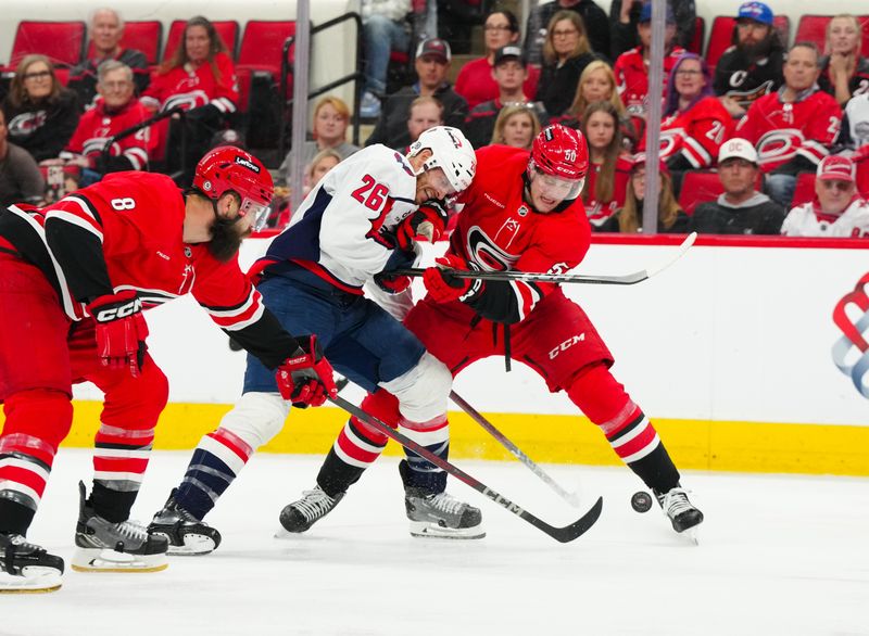 Apr 2, 2025; Raleigh, North Carolina, USA;  Washington Capitals center Nic Dowd (26) and Carolina Hurricanes left wing Eric Robinson (50) battle over the puck during the second period at Lenovo Center. Mandatory Credit: James Guillory-Imagn Images