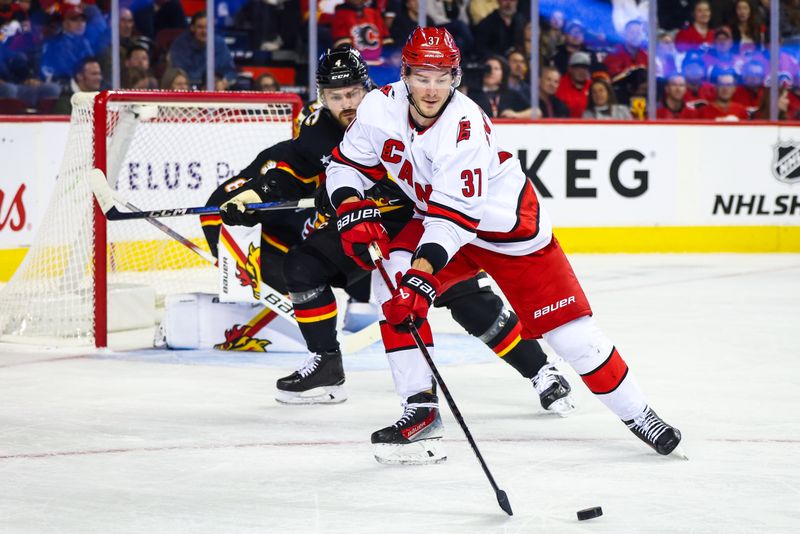 Oct 24, 2024; Calgary, Alberta, CAN; Carolina Hurricanes right wing Andrei Svechnikov (37) controls the puck against Calgary Flames defenseman Rasmus Andersson (4) during the first period at Scotiabank Saddledome. Mandatory Credit: Sergei Belski-Imagn Images