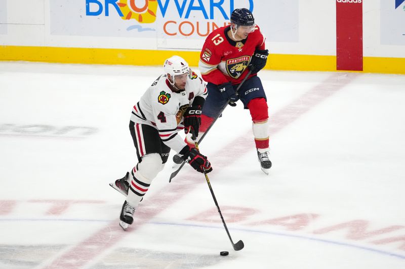 Nov 12, 2023; Sunrise, Florida, USA; Chicago Blackhawks defenseman Seth Jones (4) passes the puck away from Florida Panthers center Sam Reinhart (13) during the third period at Amerant Bank Arena. Mandatory Credit: Jasen Vinlove-USA TODAY Sports