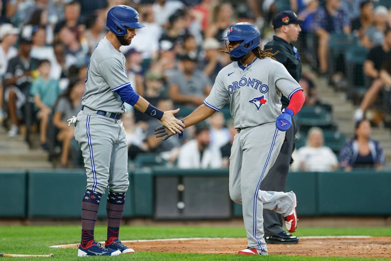 Jul 4, 2023; Chicago, Illinois, USA; Toronto Blue Jays first baseman Vladimir Guerrero Jr. (27) celebrates with designated hitter Brandon Belt (13) after scoring against the Chicago White Sox during the fourth inning at Guaranteed Rate Field. Mandatory Credit: Kamil Krzaczynski-USA TODAY Sports