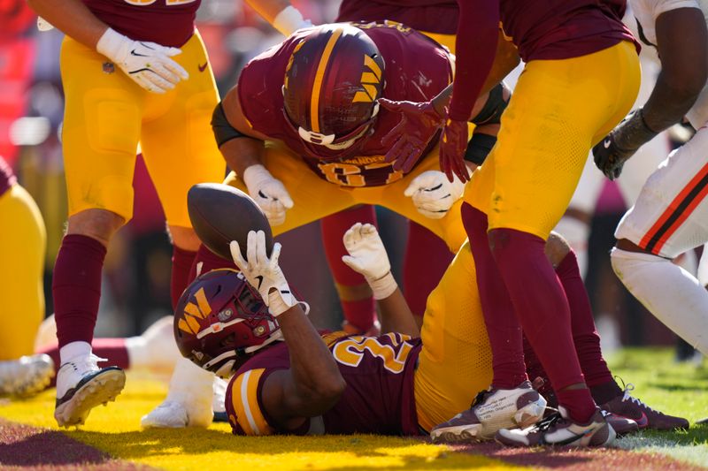 Washington Commanders running back Jeremy McNichols, bottom, celebrates his touchdown run against the Cleveland Browns with Nick Allegretti, top, during the second half of an NFL football game in Landover, Md., Sunday, Oct. 6, 2024. (AP Photo/Stephanie Scarbrough)