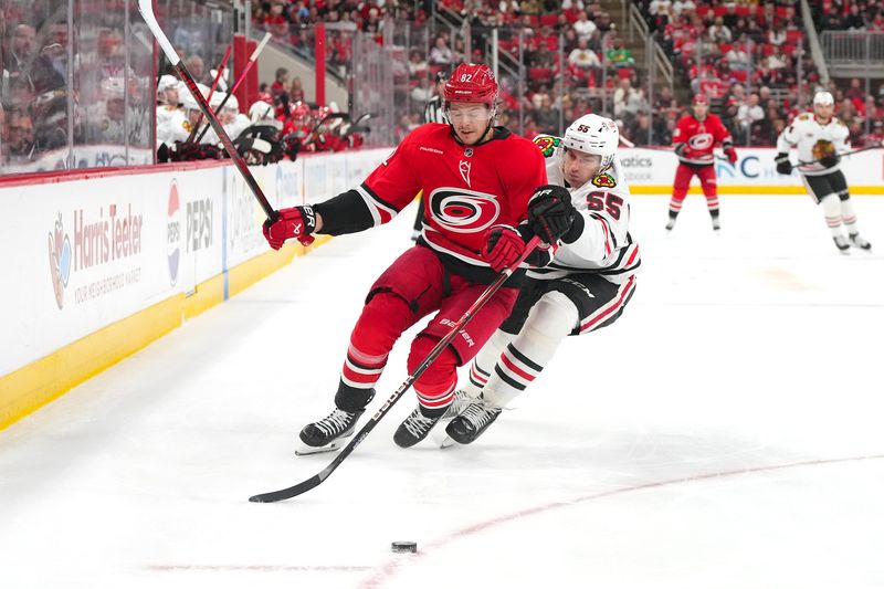 Jan 22, 2026; Raleigh, North Carolina, USA;  Carolina Hurricanes center Jesperi Kotkaniemi (82) and Chicago Blackhawks defenseman Artyom Levshunov (55) chase after the puck during the third period at Lenovo Center. Mandatory Credit: James Guillory-Imagn Images