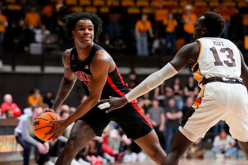 Feb 27, 2024; Laramie, Wyoming, USA; UNLV Runnin' Rebels center Luis Rodriguez (15) looks to pass against Wyoming Cowboys guard Akuel Kot (13) during the first half at Arena-Auditorium. Mandatory Credit: Troy Babbitt-USA TODAY Sports