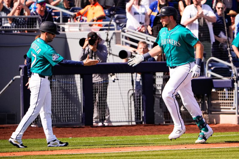 Feb 24, 2026; Peoria, Arizona, USA; Seattle Mariners catcher Cal Raleigh (29) reacts with third base coach Carlos Cardoza (57) after hitting a two-run home run against the Chicago White Sox during the third inning in Peoria, Arizona. Mandatory Credit: Arianna Grainey-Imagn Images
