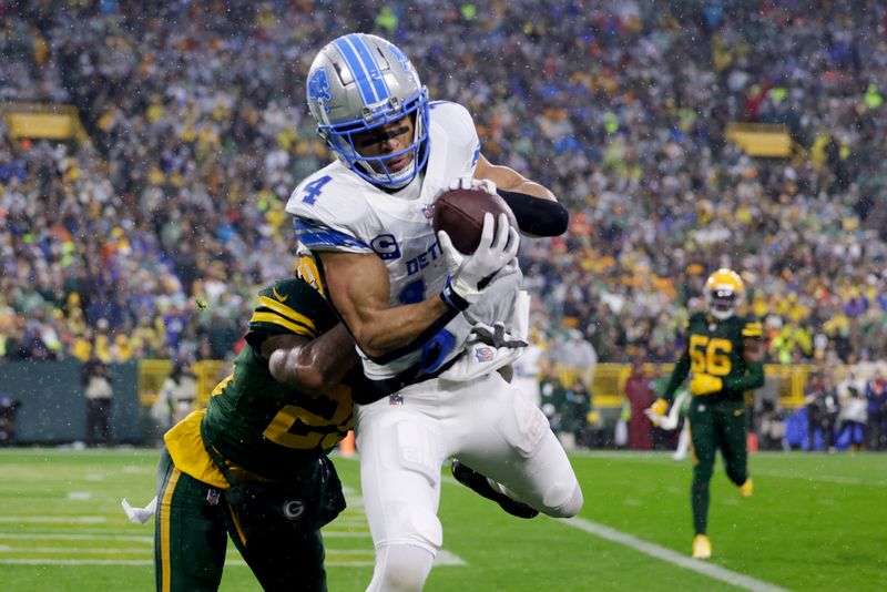 Detroit Lions wide receiver Amon-Ra St. Brown (14) catches a touchdown past Green Bay Packers cornerback Keisean Nixon during the first half of an NFL football game Sunday, Nov. 3, 2024, in Green Bay, Wis. (AP Photo/Matt Ludtke)