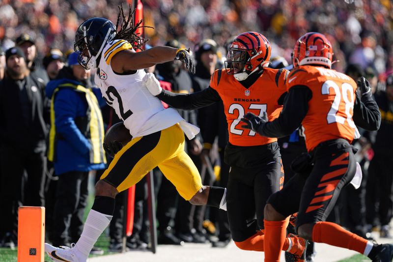 Pittsburgh Steelers running back Najee Harris, left, runs the ball against Cincinnati Bengals safety Jordan Battle (27) during the first half of an NFL football game Sunday, Dec. 1, 2024, in Cincinnati. (AP Photo/Jeff Dean)