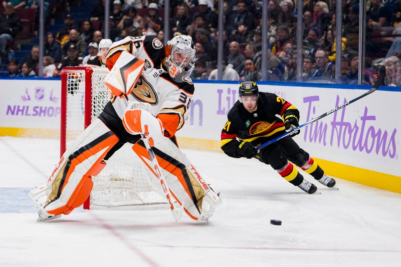 Nov 28, 2023; Vancouver, British Columbia, CAN; Anaheim Ducks goalie John Gibson (36) handles the puck as Vancouver Canucks forward Nils Hoglander (21) watches in the second period at Rogers Arena. Mandatory Credit: Bob Frid-USA TODAY Sports