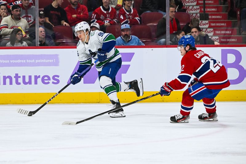 Nov 12, 2023; Montreal, Quebec, CAN; Vancouver Canucks left wing Andrei Kuzmenko (96) plays the puck against Montreal Canadiens right wing Cole Caufield (22) during the third period at Bell Centre. Mandatory Credit: David Kirouac-USA TODAY Sports