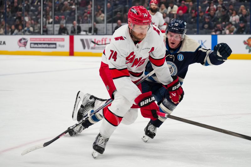 Nov 23, 2024; Columbus, Ohio, USA;  Carolina Hurricanes defenseman Jaccob Slavin (74) skates for the puck against Columbus Blue Jackets left wing Dmitri Voronkov (10) in the first period at Nationwide Arena. Mandatory Credit: Aaron Doster-Imagn Images